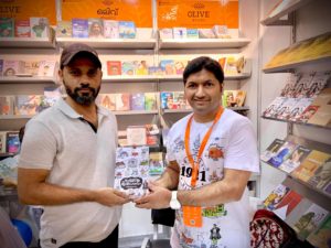 Artist Shaf Beypore receives a signed copy of ഹിന്ദിന്റെ ഇതിഹാസം and the ‘Ithihaasam’ mug at the Olive Books stall in Sharjah international Book Fair. 